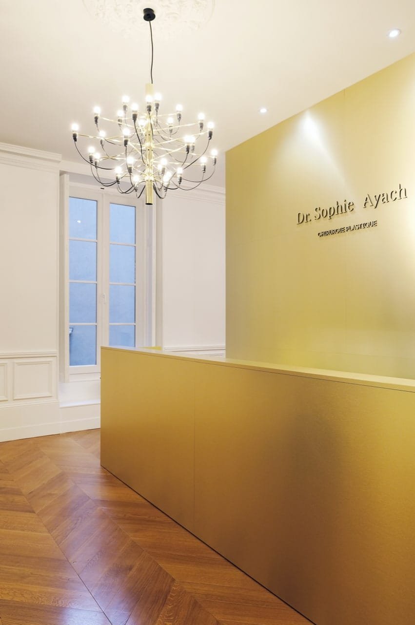 Banque d'accueil sur mesure en finition dorée installée dans un cabinet médical